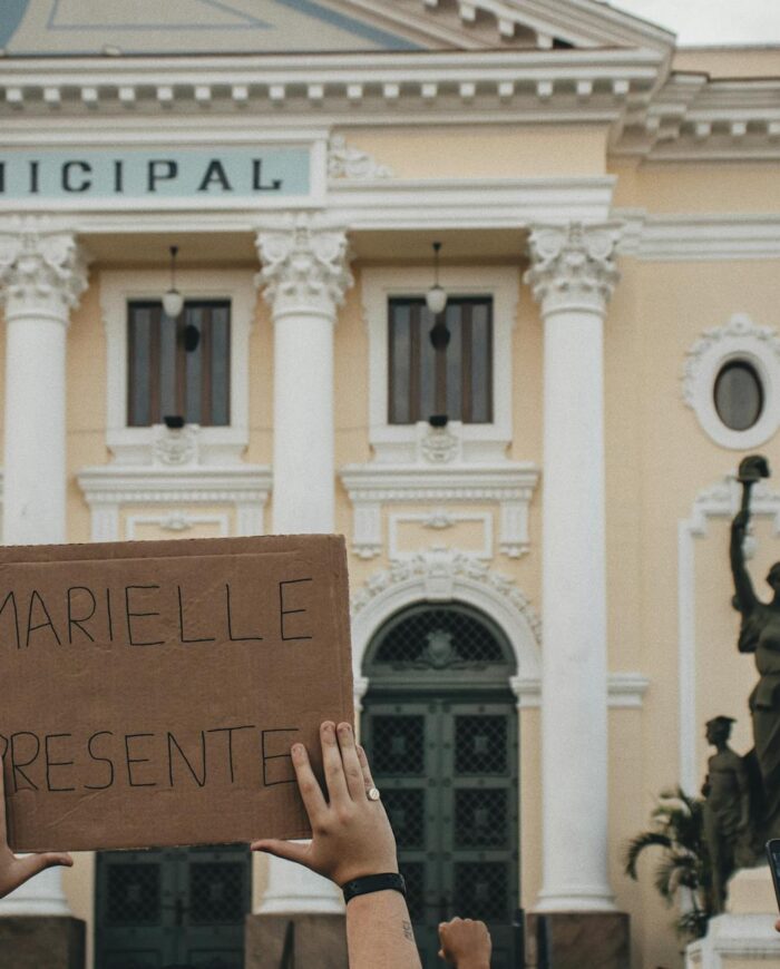 Crowd holding a sign 'MARIELLE PRESENTE' at Rio's city hall.