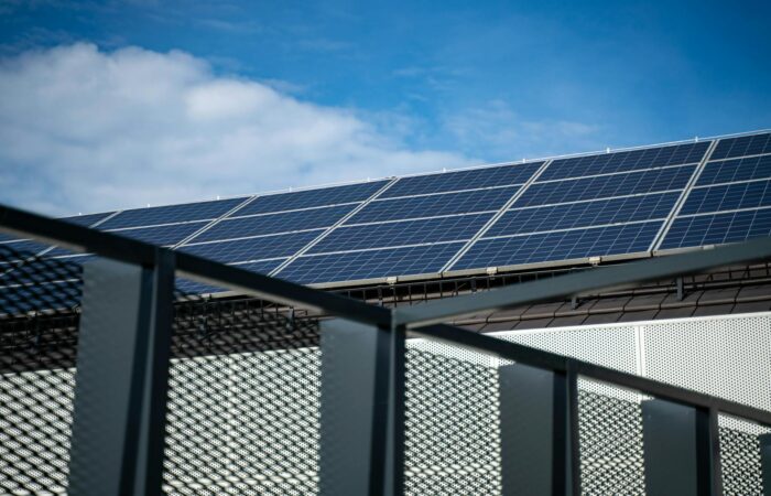 Close-up view of modern solar panels on a rooftop against a clear blue sky, representing clean energy.