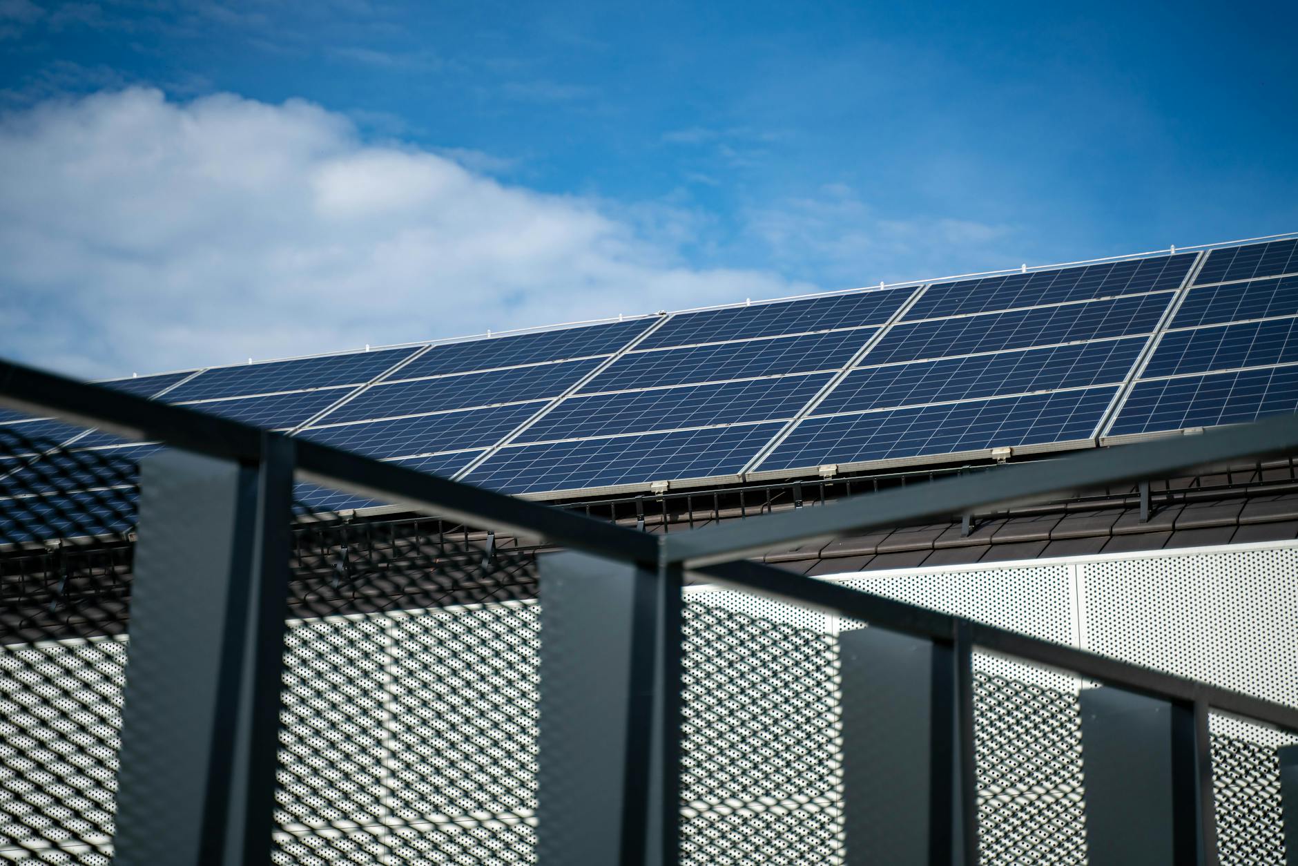 Close-up view of modern solar panels on a rooftop against a clear blue sky, representing clean energy.