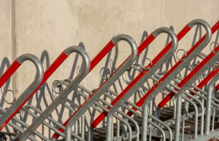 Empty bicycle rack with red and silver metal bars creating a geometric pattern in outdoor setting. Empty bicycle rack with red and silver metal bars creating a geometric pattern in outdoor setting.