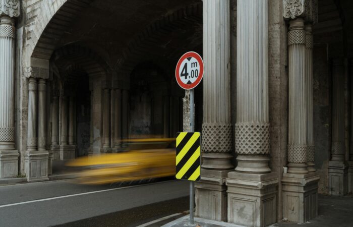 A yellow taxi speeds through a stone tunnel with classic columns and arches, creating a blur of motion. A yellow taxi speeds through a stone tunnel with classic columns and arches, creating a blur of motion.