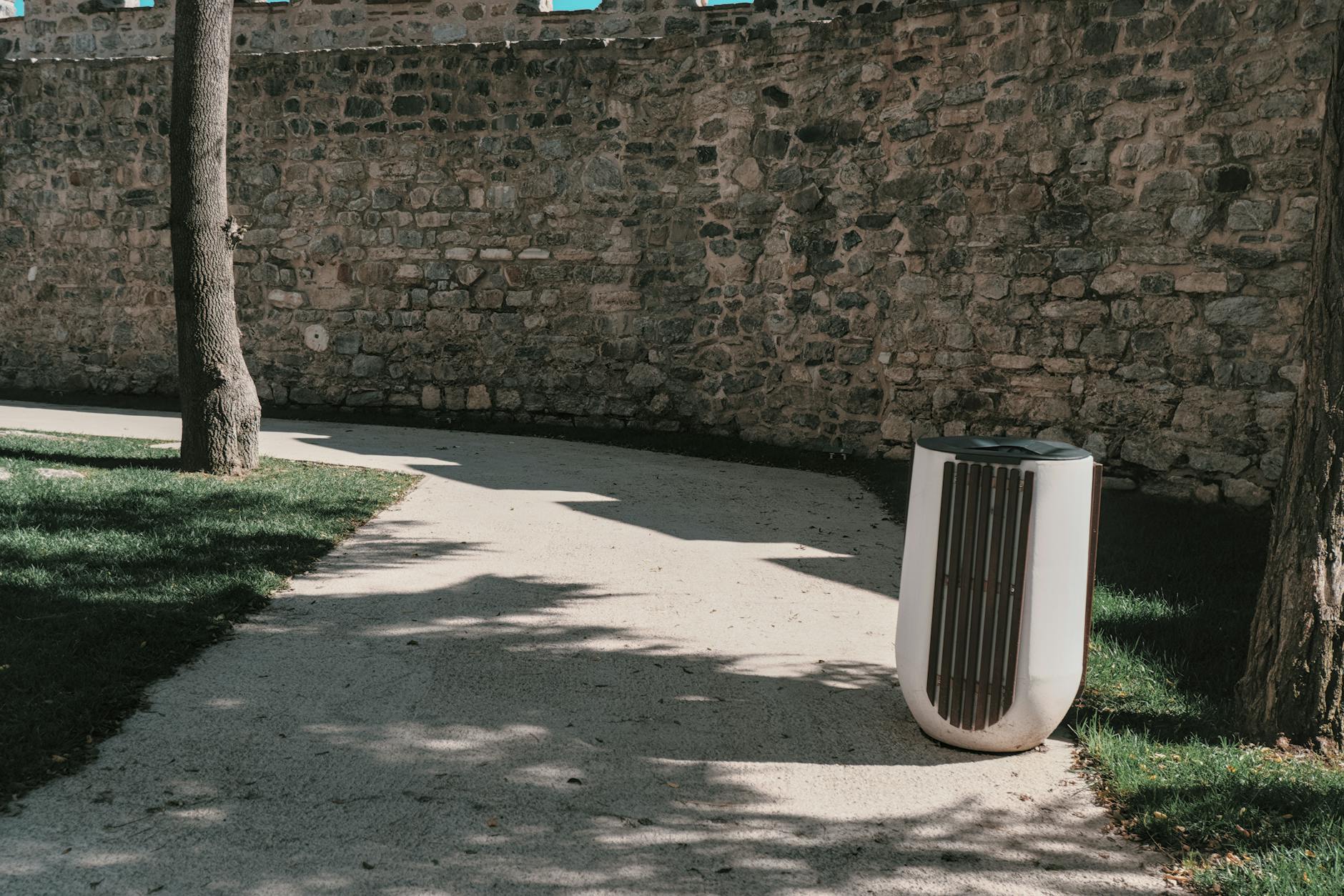 A tranquil path along a stone wall in a sunlit Istanbul park, showcasing nature and architecture.