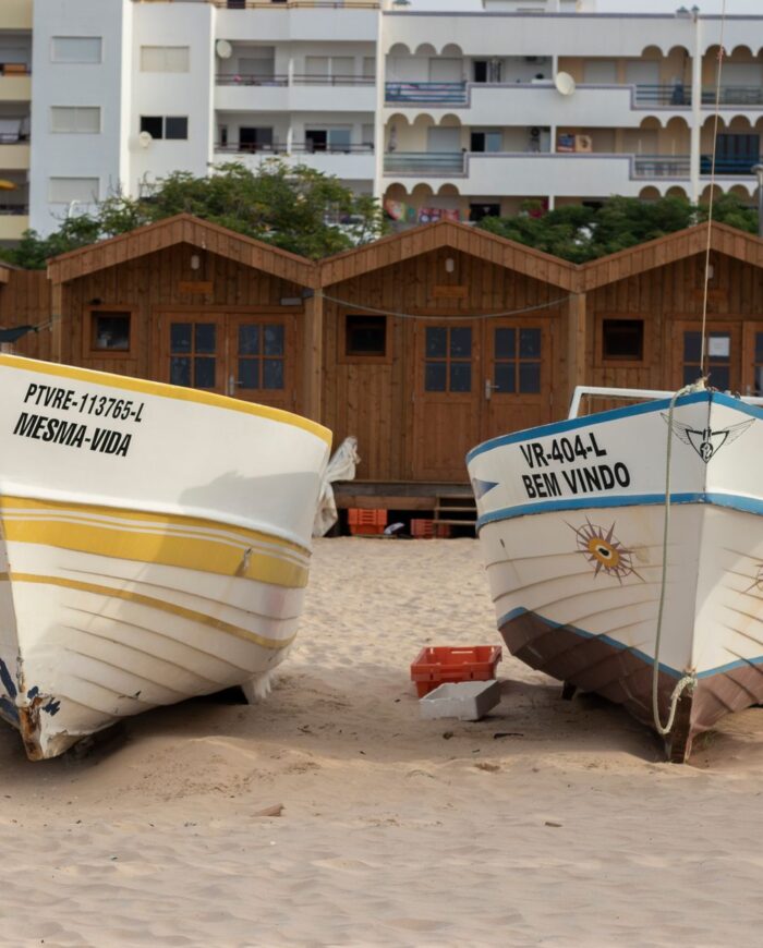 Colorful fishing boats resting on sandy Monte Gordo beach, Faro, Portugal.