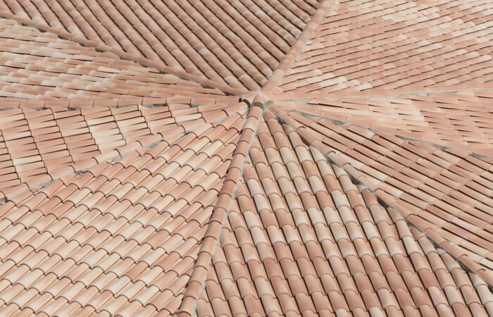 Detailed view of terracotta roof shingles forming a geometric pattern from above.
