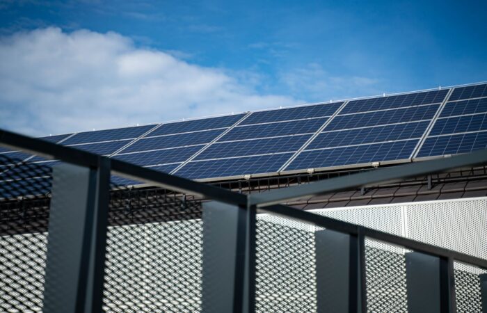 Close-up view of modern solar panels on a rooftop against a clear blue sky, representing clean energy. Close-up view of modern solar panels on a rooftop against a clear blue sky, representing clean energy.