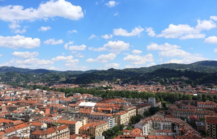 Stunning aerial view of Turin, Italy with red rooftops and lush green hills under a clear blue sky. Stunning aerial view of Turin, Italy with red rooftops and lush green hills under a clear blue sky.