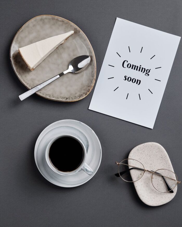 Stylish flatlay featuring coffee, slice of cheesecake, and eyeglasses on paper.