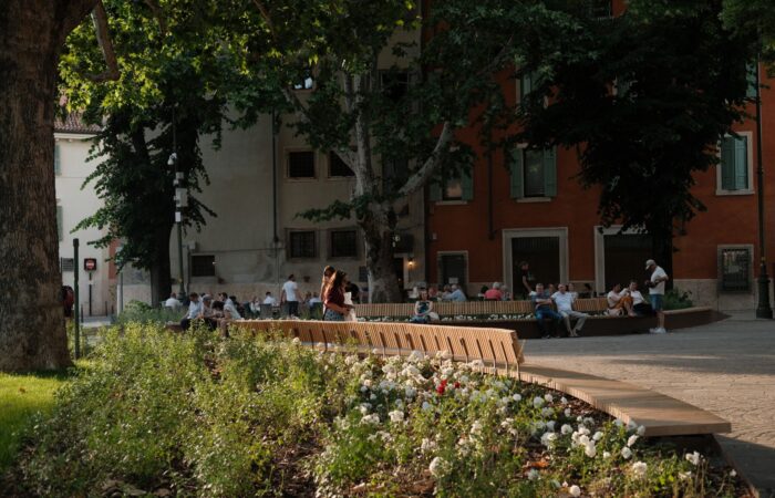 People relax on benches surrounded by flowers in Verona’s charming architecture. People relax on benches surrounded by flowers in Verona's charming architecture.