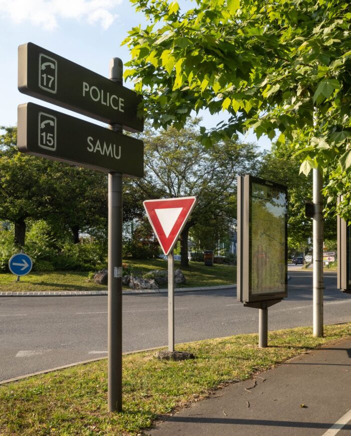 Roundabout in France with traffic signs and lush greenery on a sunny day.
